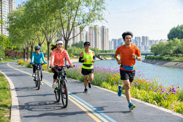 市民在城市滨河绿道上骑行、跑步，享受自然与运动