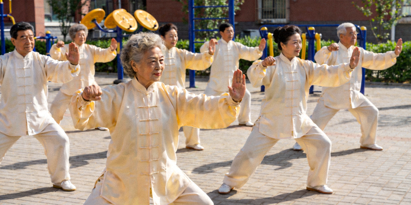 老年群体在社区广场整齐地练习太极拳，动作舒缓而有力
