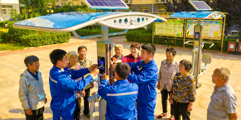 工作人员正在安装新一代太阳能智能健身器材，居民围观体验