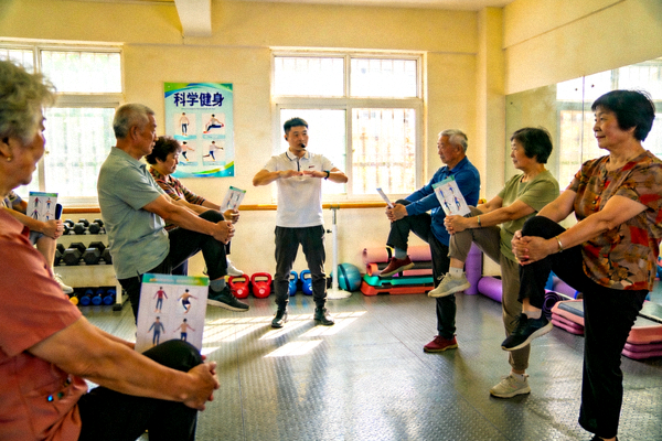 社区活动室内，专业教练正在指导中老年人进行科学安全的健身操练习