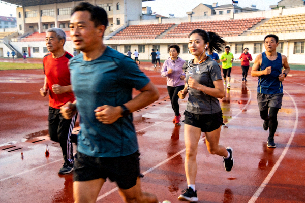 学校体育场馆在周末向公众开放，市民正在标准跑道上跑步锻炼