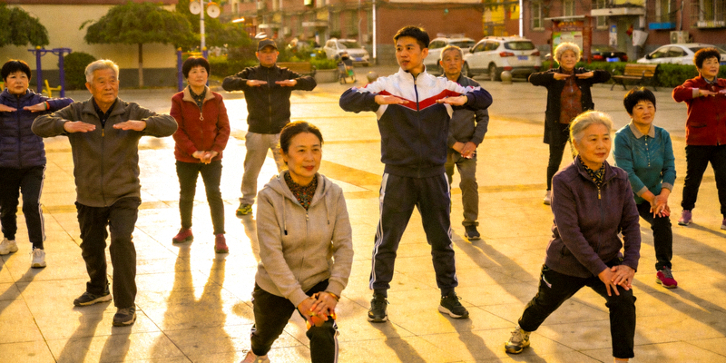 社会体育指导员在社区广场带领居民进行科学热身运动，现场气氛活跃