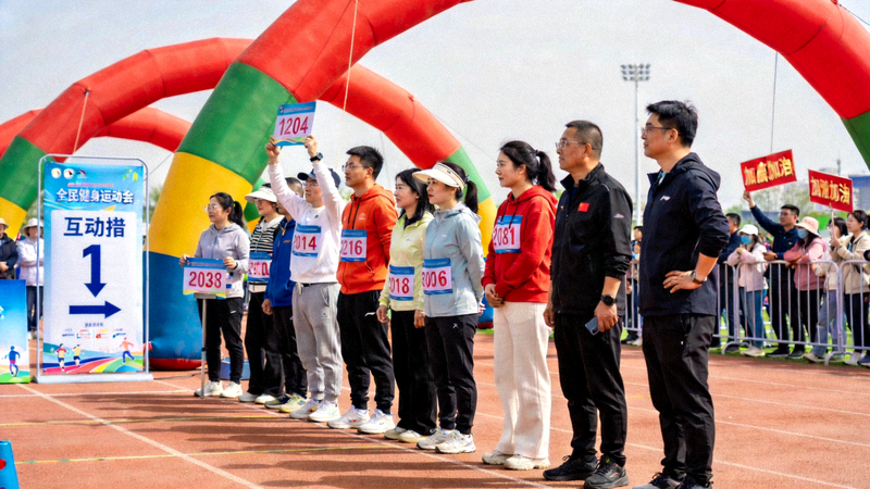 全民健身运动会现场，参赛者在趣味项目区排队参与互动比赛